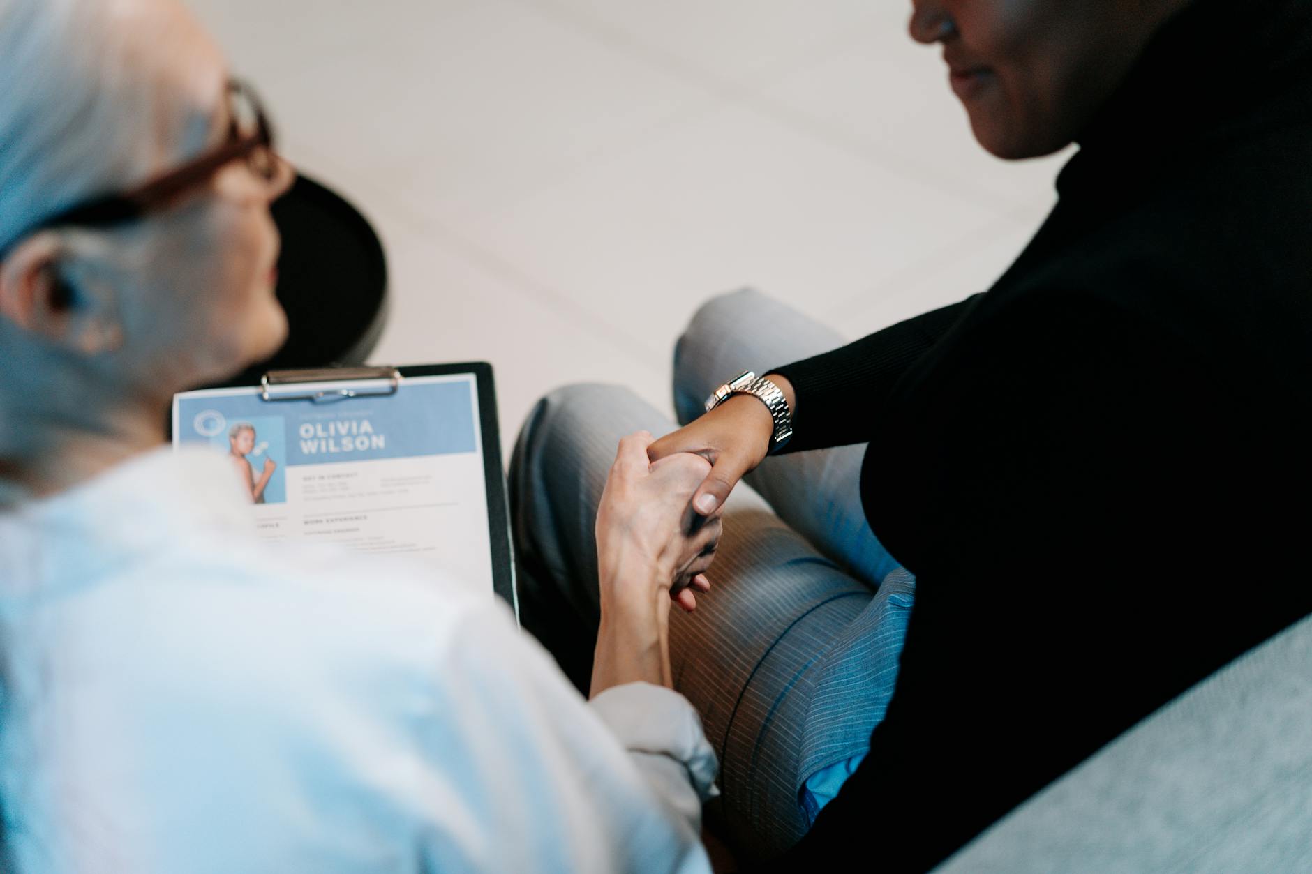 Two professionals shaking hands across a desk during a business evaluation meeting, representing partnership trust and agency selection.