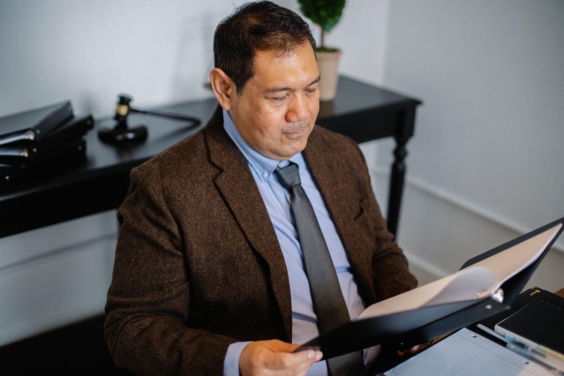 Real estate investor reviewing loan documents and financial paperwork at desk with calculator and laptop