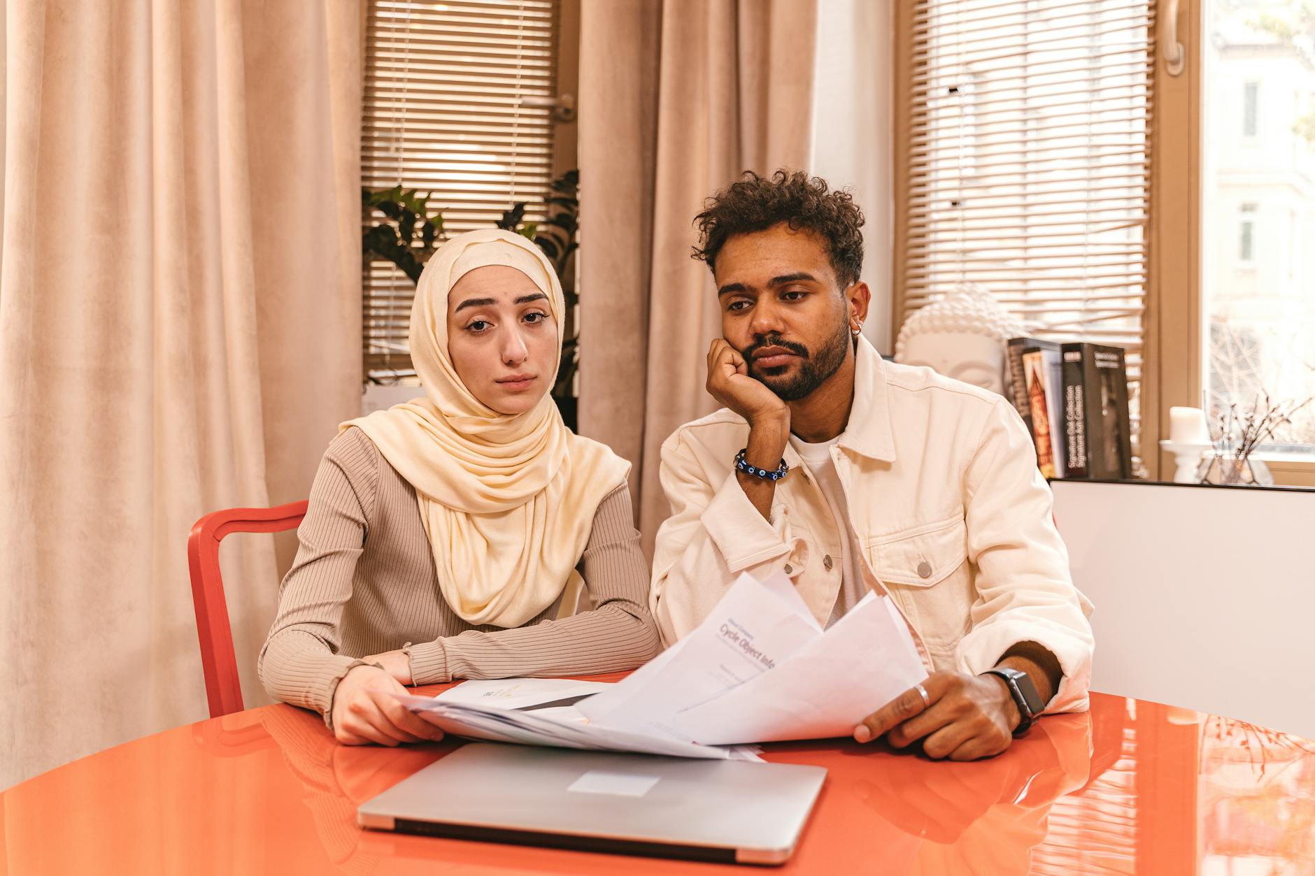 Young couple reviewing mortgage pre-approval documents with real estate agent at kitchen table