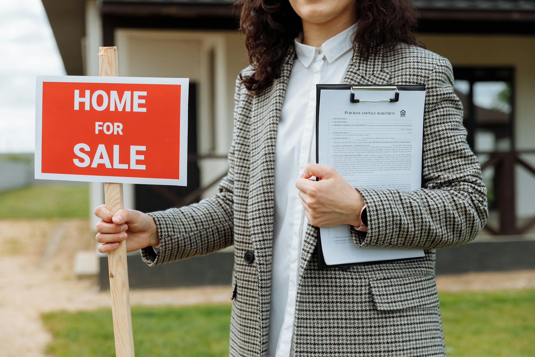 Real estate agent and client reviewing and signing buyer agency agreement contract at desk with documents and pen