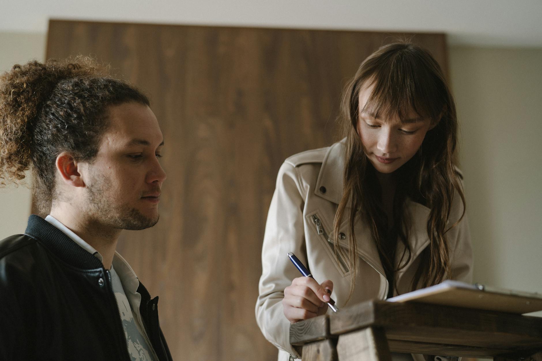 Young couple sitting at table reviewing mortgage documents and taking notes before purchasing home
