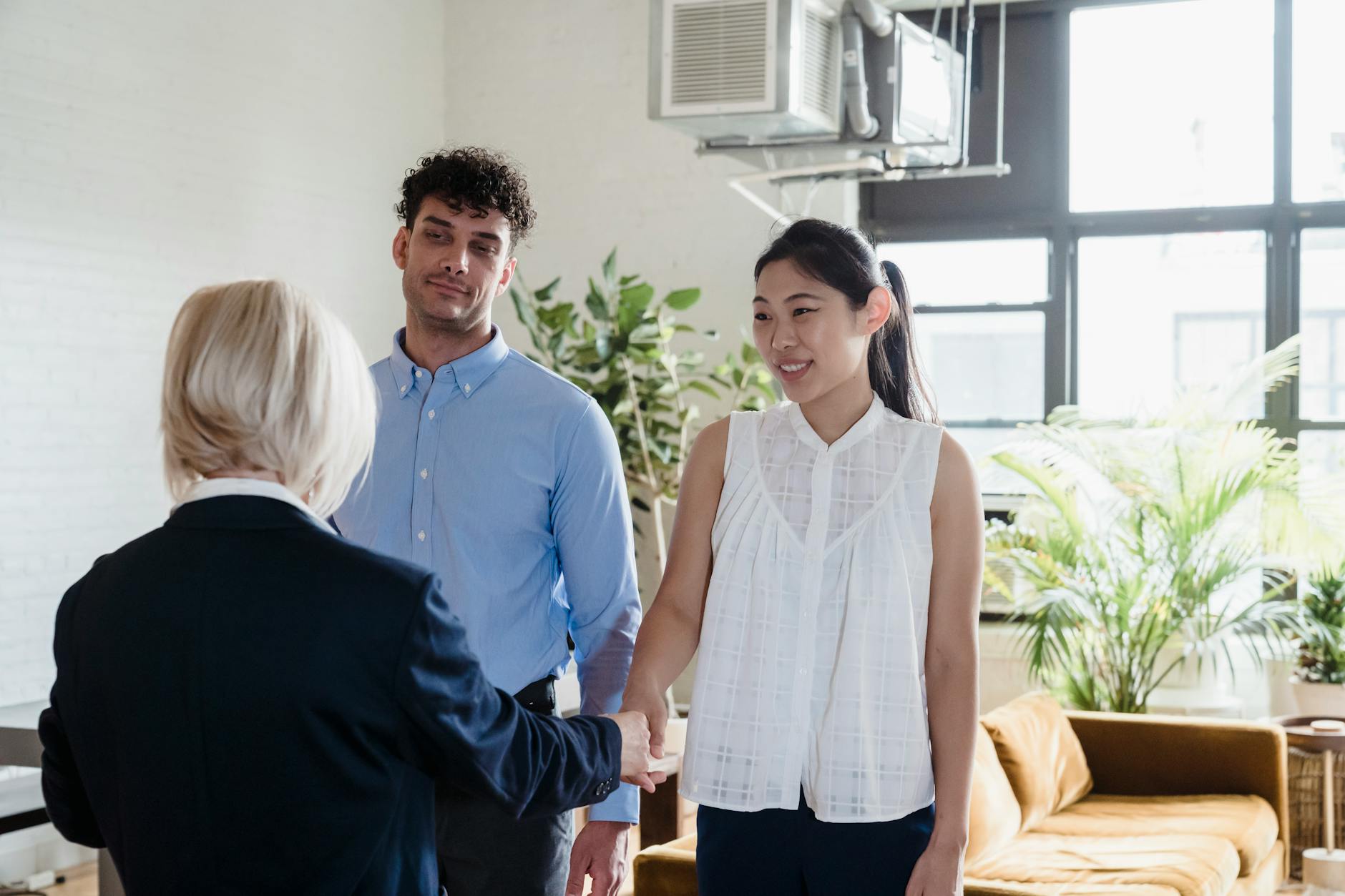 Professional real estate agent discussing home buying options with Korean American couple in modern office