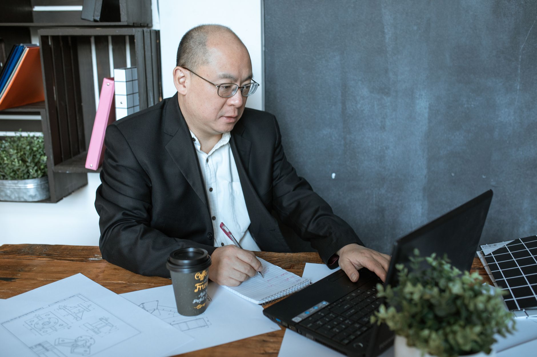 Korean American entrepreneur reviewing financial documents and tax forms at desk