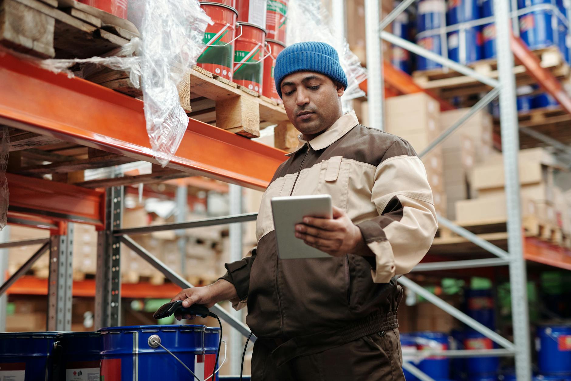 Warehouse worker using handheld scanner to price and catalog stacked boxes of liquidation inventory for resale