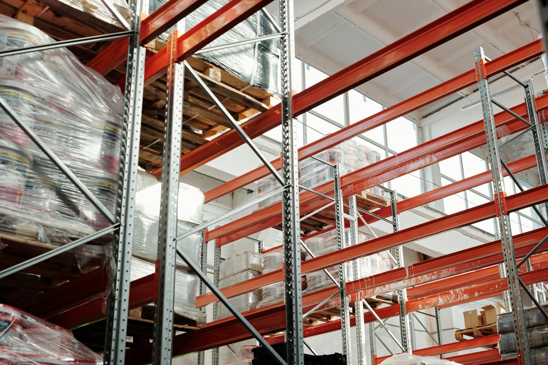 Workers organizing and sorting stacked liquidation pallets in a large warehouse facility for resale