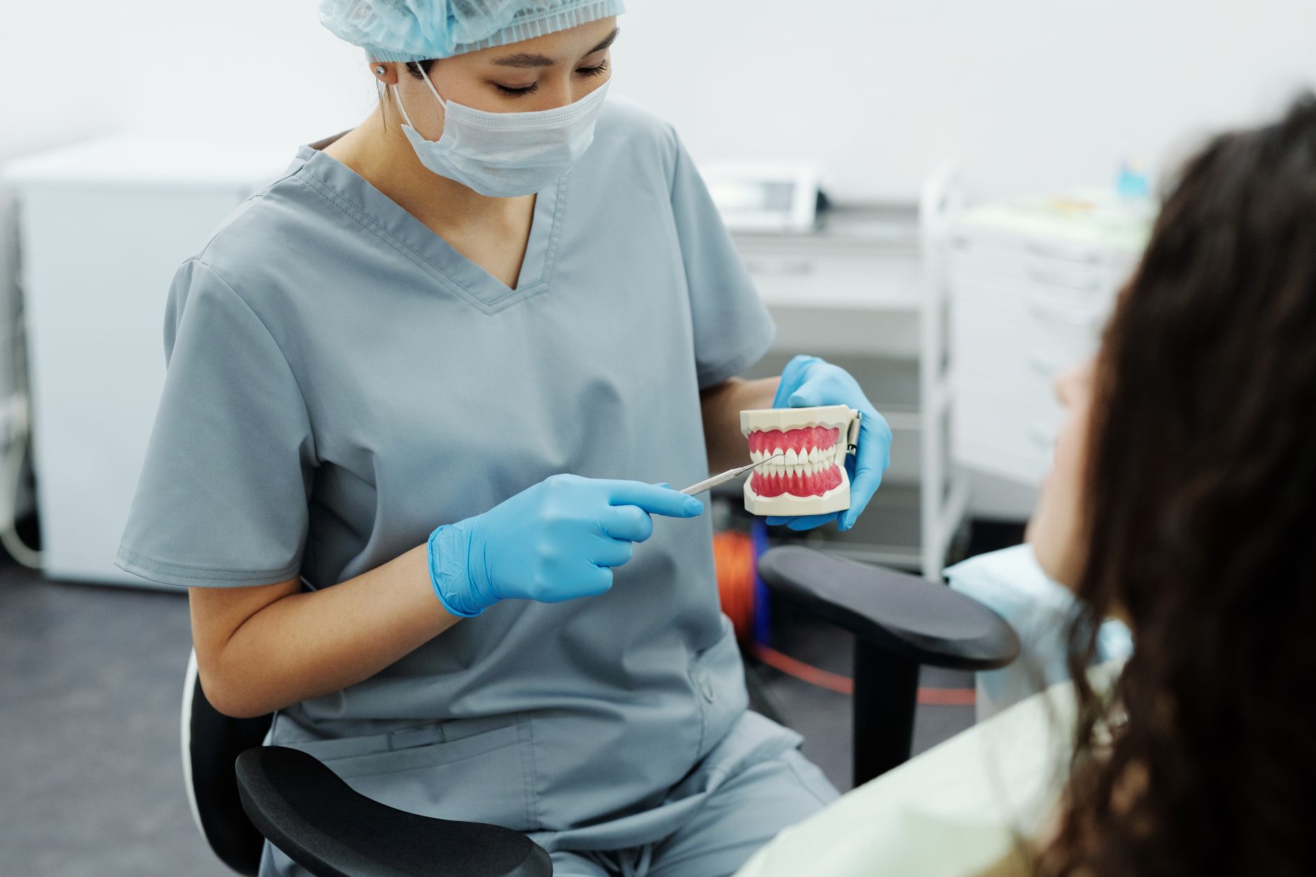 Orthodontist examining patient's teeth during consultation to discuss braces treatment options and costs
