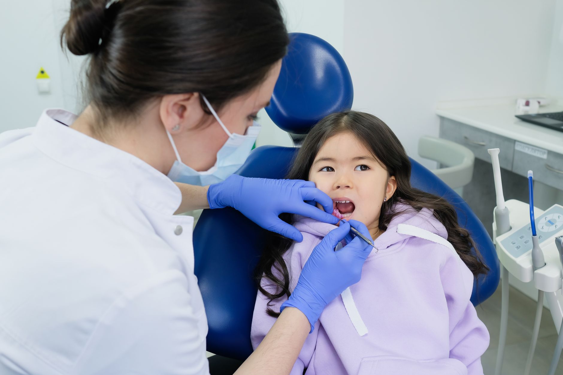 Young child smiling with open mouth during dental examination with orthodontist checking teeth alignment