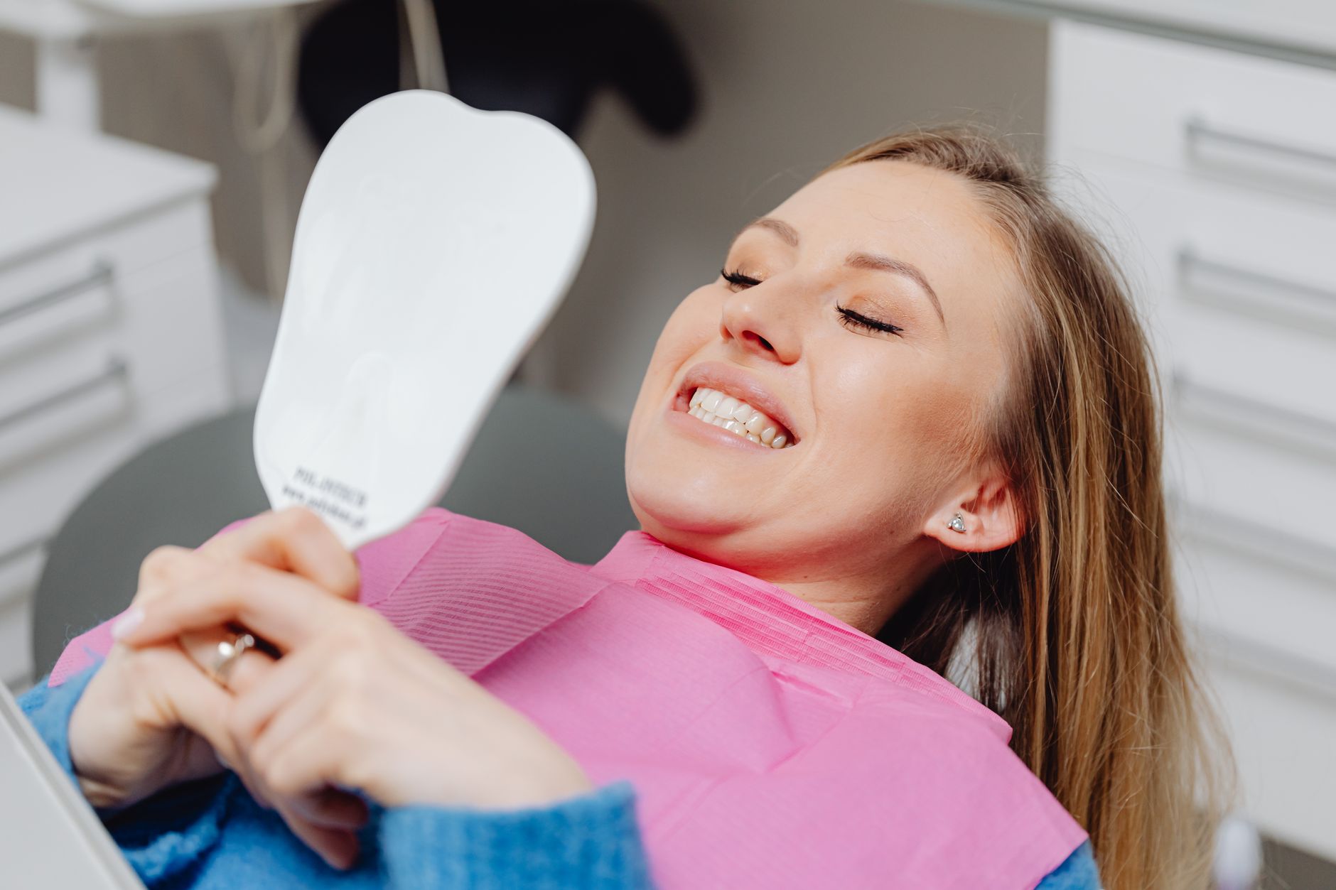 Young woman examining her teeth in mirror, concerned about orthodontic alignment changes