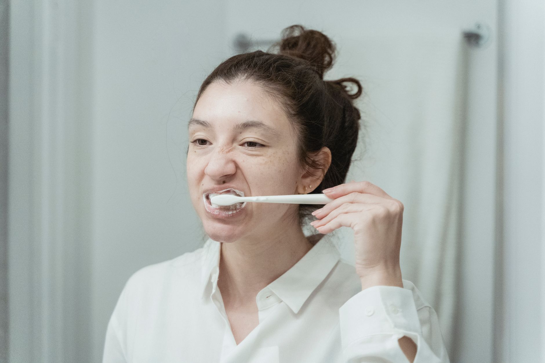 Woman demonstrating proper tooth brushing technique for daily dental crown maintenance and oral care