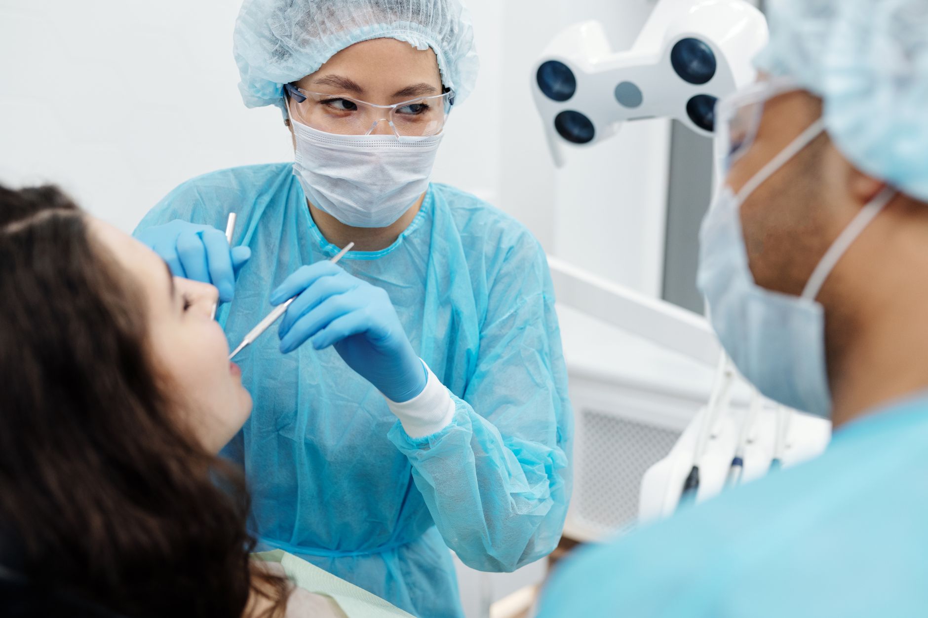 A dentist in protective gear examines a patient in a modern dental clinic.