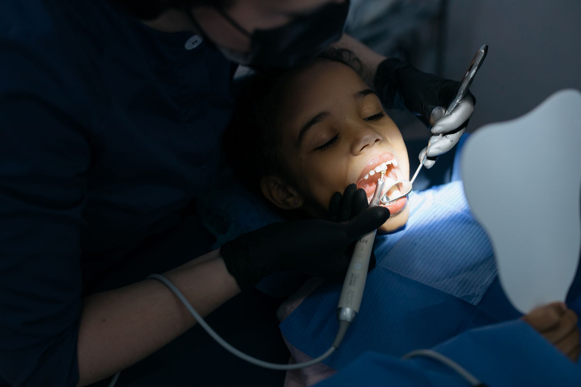 Pediatric dentist performing oral examination on young child patient in modern dental clinic