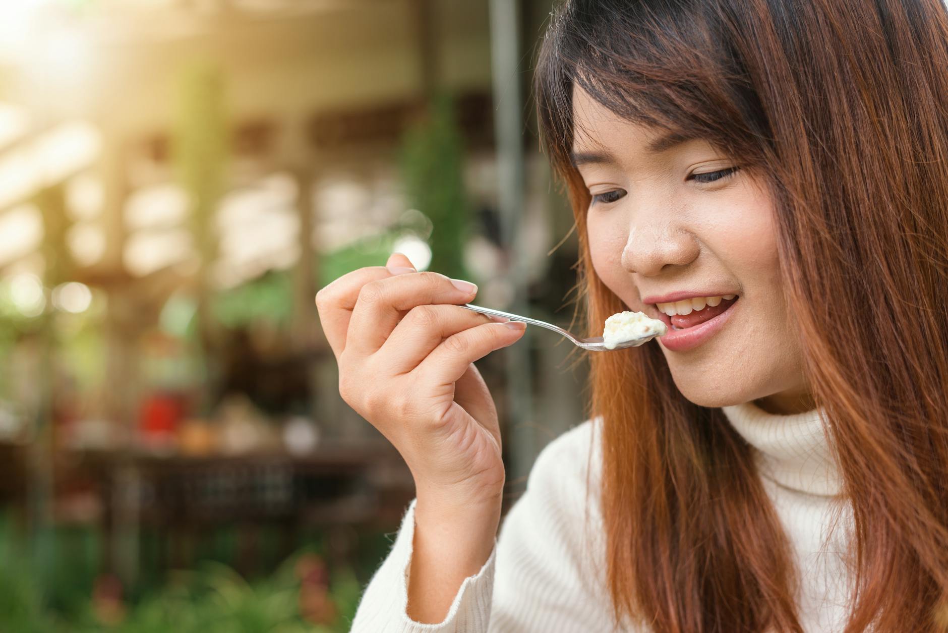 Woman carefully eating food while wearing clear dental aligners during orthodontic treatment