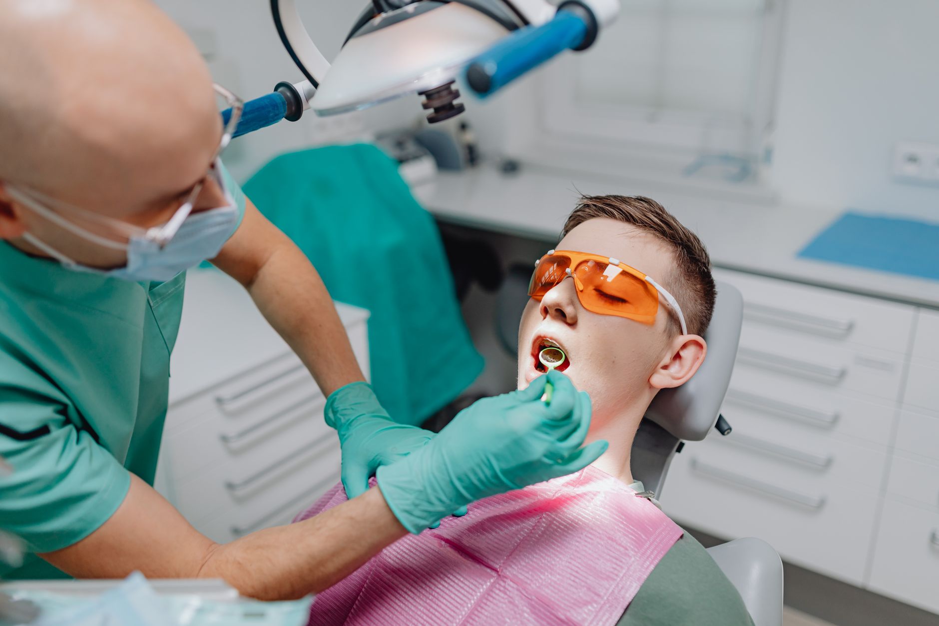 Dentist in protective gear examining a patient in a dental chair during a consultation visit