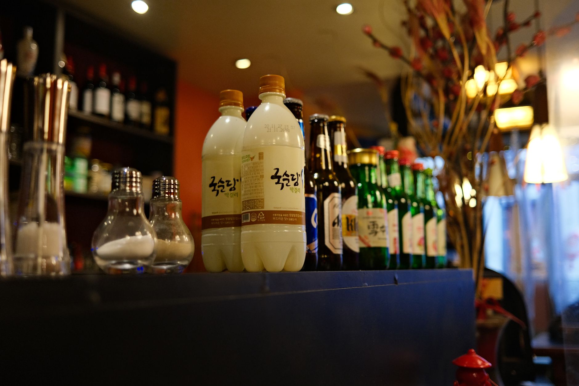 Young adults enjoying traditional Korean spirits at a trendy bar with modern ambiance and cultural decor
