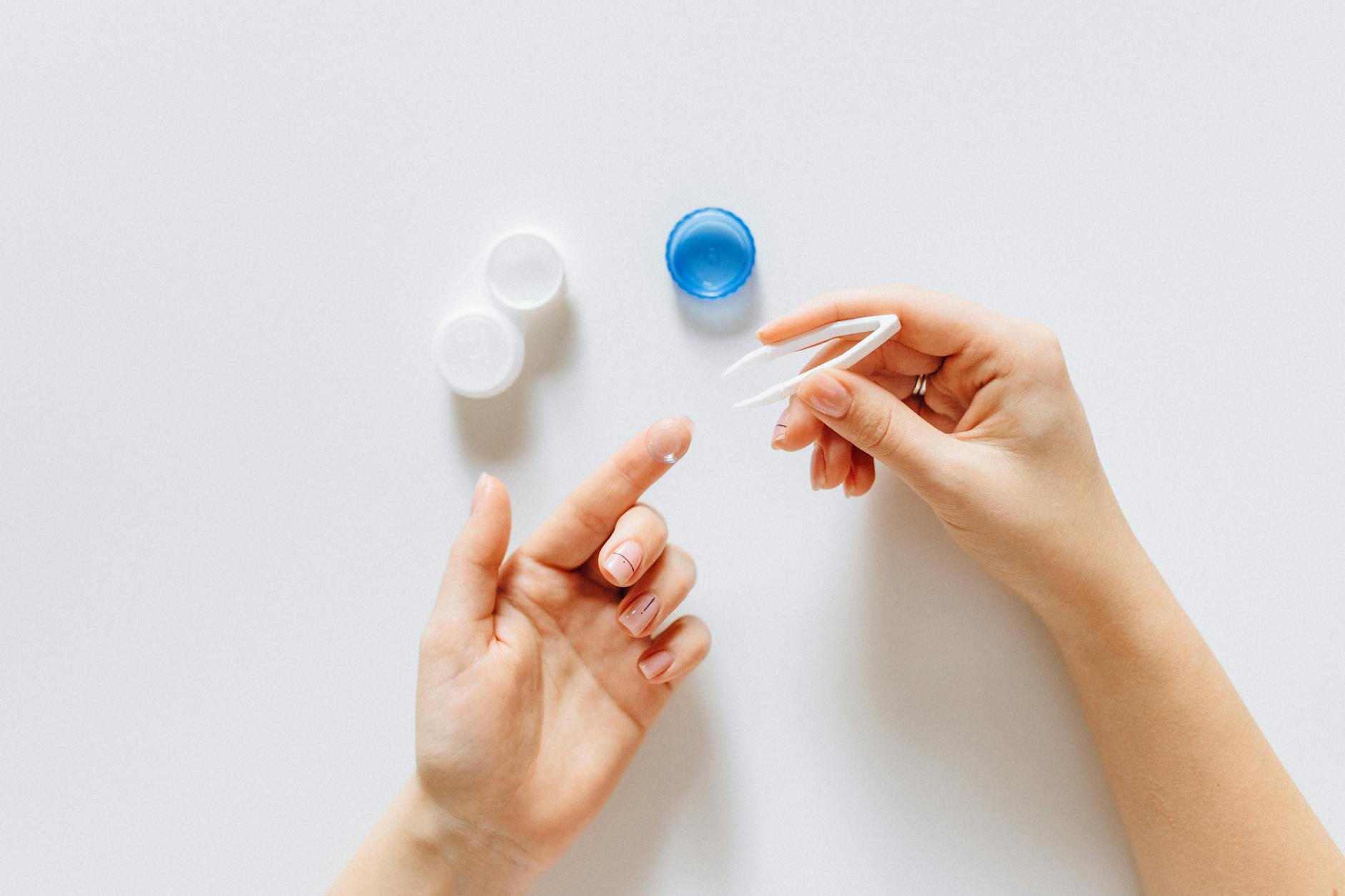 Young woman carefully inserting a contact lens into her eye with steady hands and focused expression