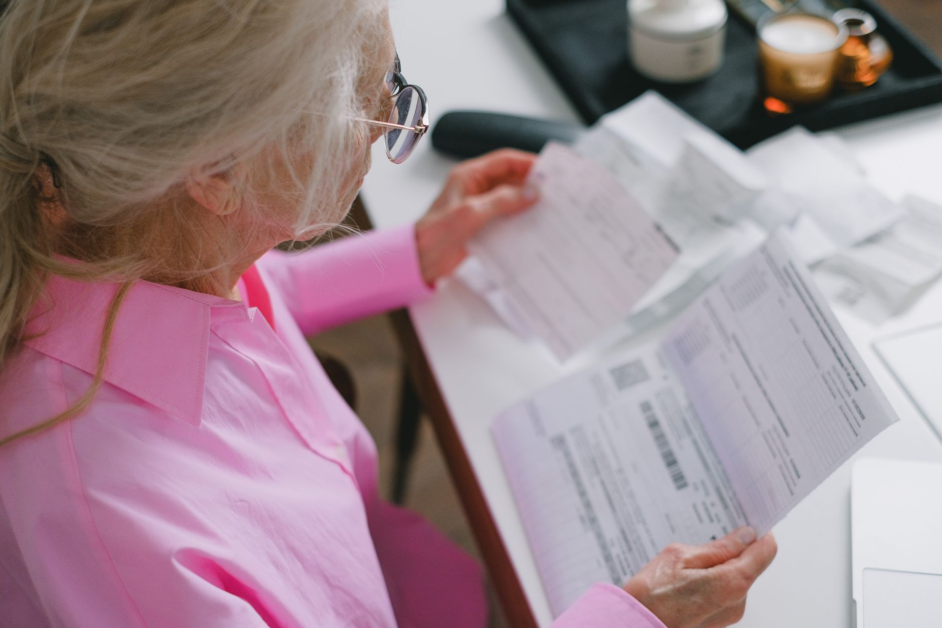Older Asian woman reviewing Medicare insurance paperwork and documents at home