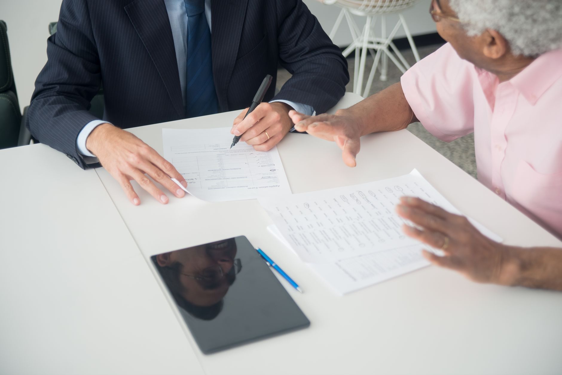 Older adult reviewing medical insurance documents with healthcare professional during consultation meeting