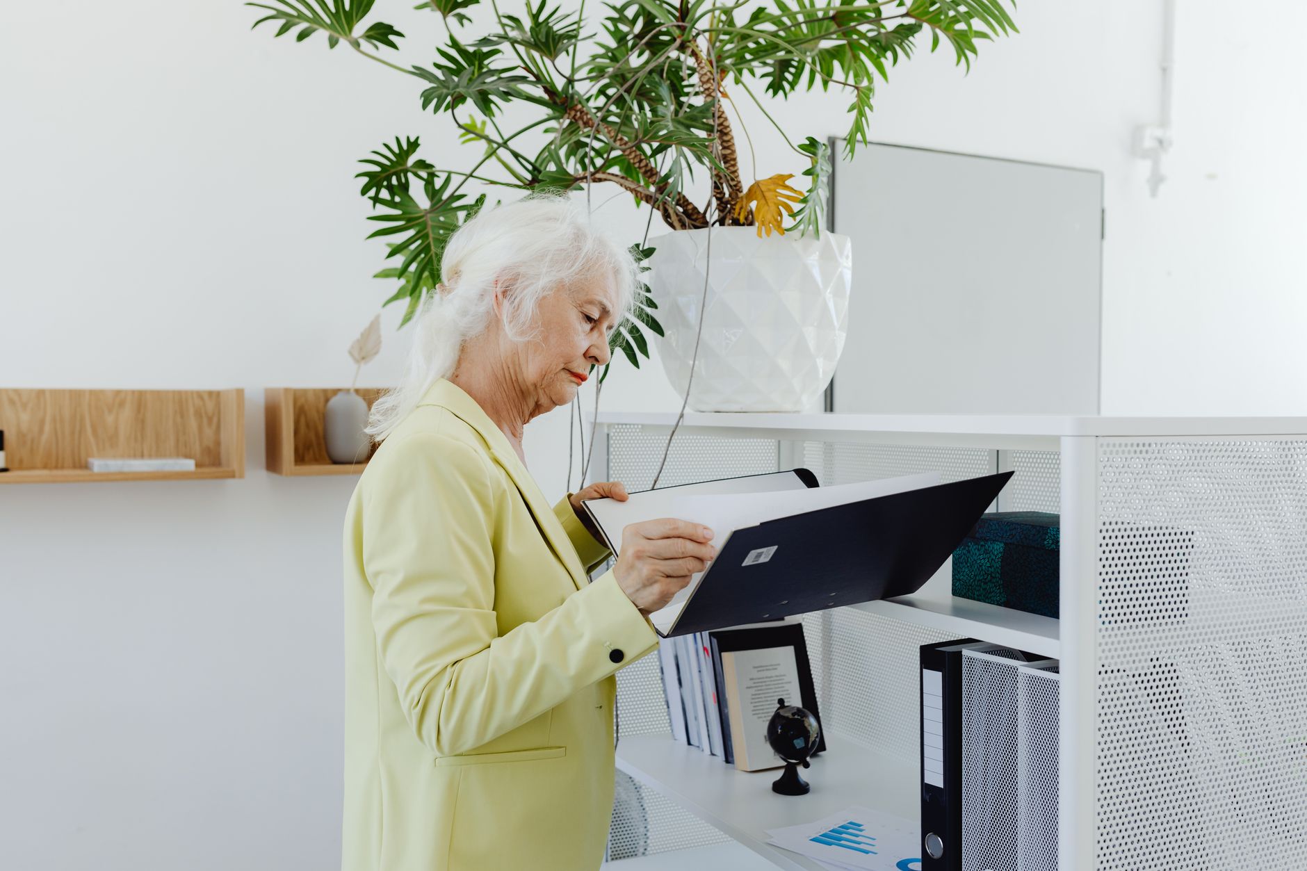 Older woman reviewing medical insurance documents and paperwork at home with concerned expression