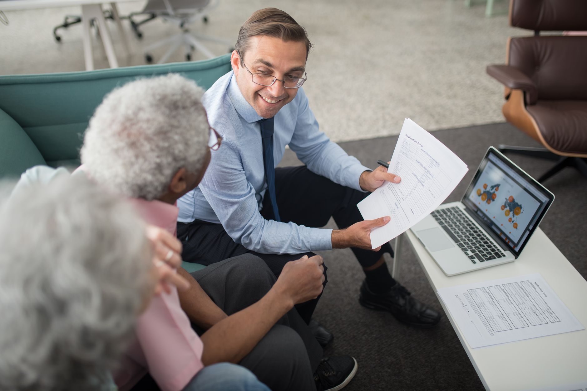 Medicare insurance agent discussing coverage options with an older adult client in a professional office setting