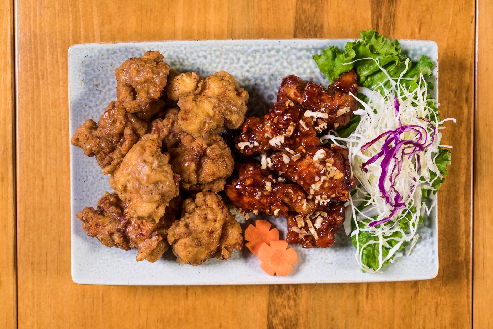 Appetizing crispy and glazed chicken with fresh vegetables on a plate.
