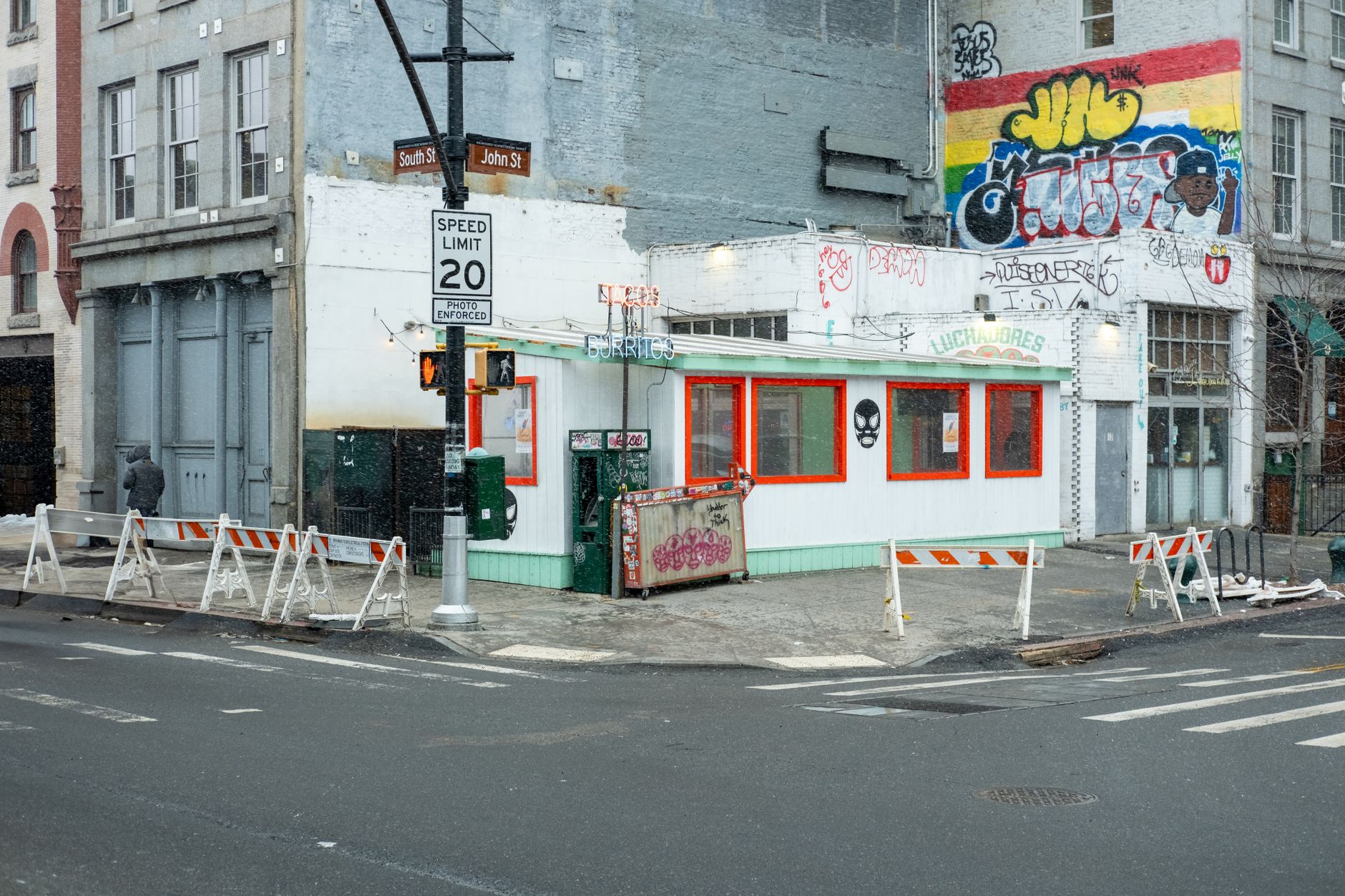 Street corner in snow with burrito stand and graffiti in New York City.