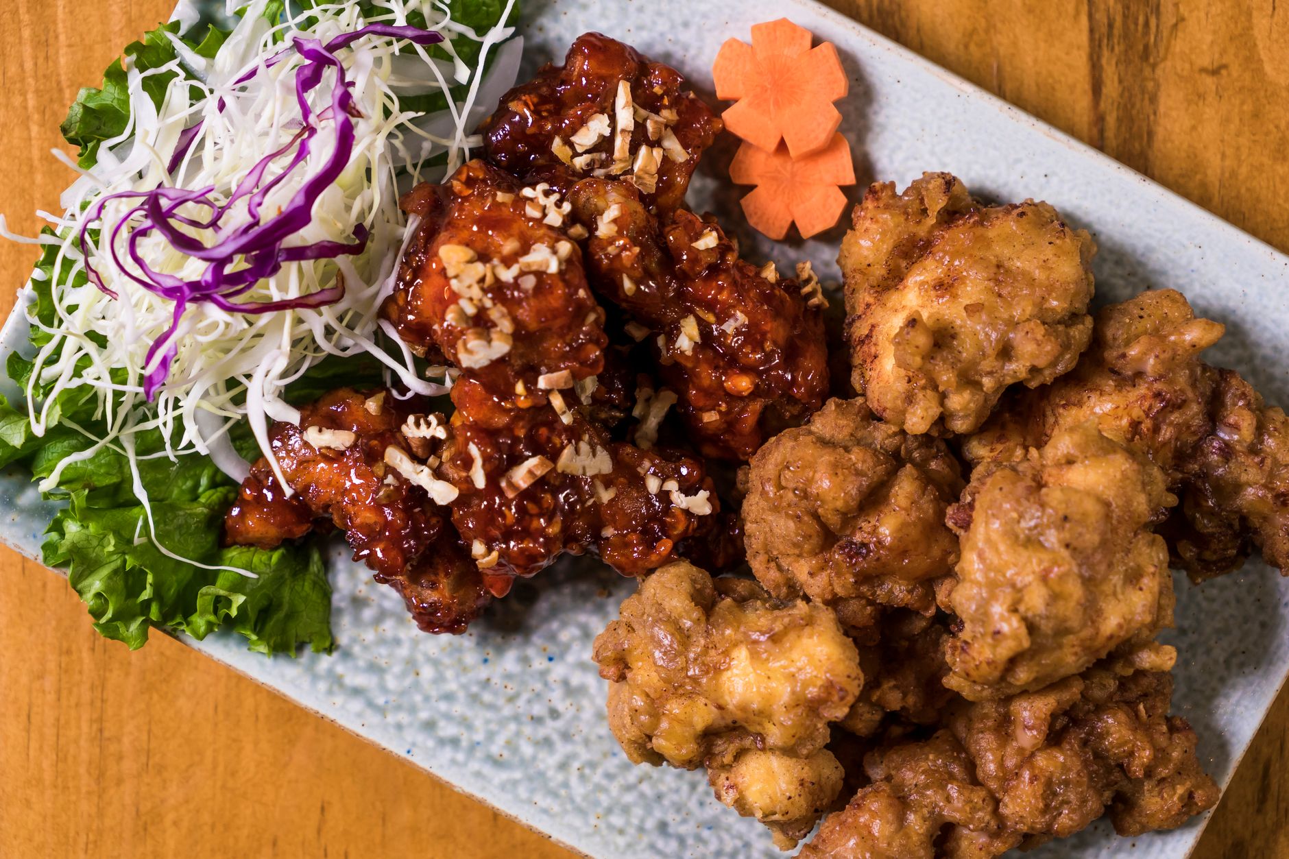 Close-up of a Korean fried chicken platter with garnishes, perfect for food enthusiasts.