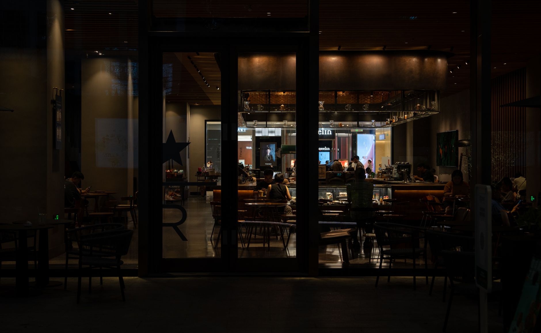 Warm and inviting nighttime interior view of a modern cafe with patrons enjoying the ambiance.