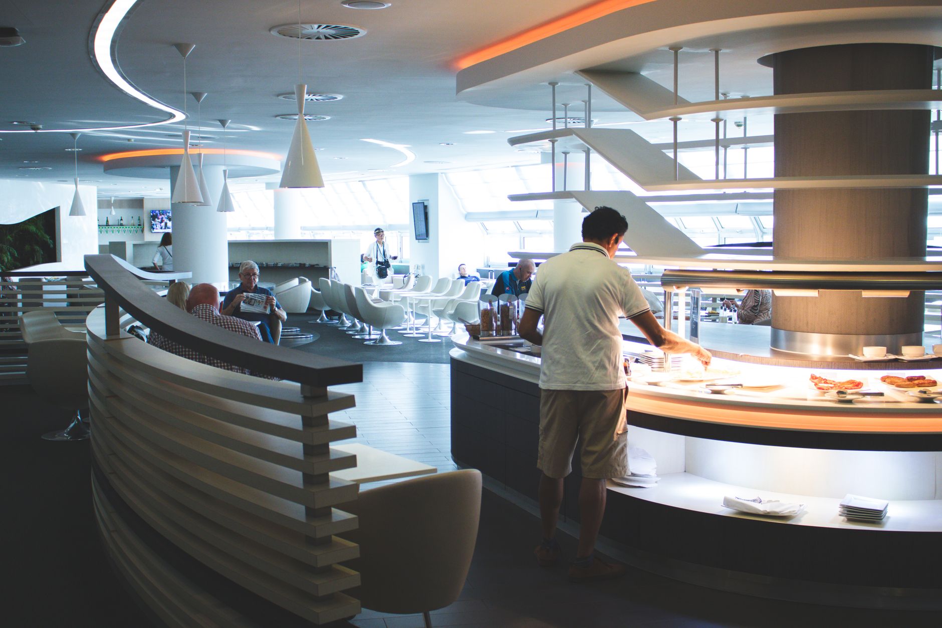 Contemporary airport bar with modern seating, cocktails on counter, and ambient lighting for travelers