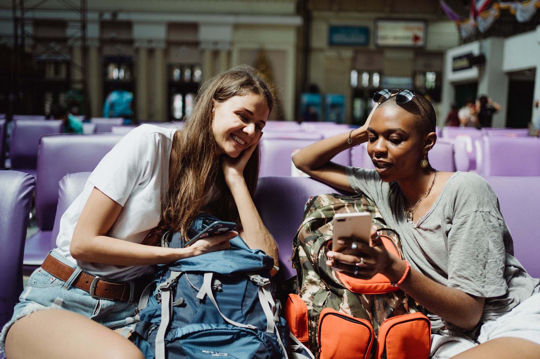 Young travelers enjoying drinks and conversation in a contemporary airport lounge with warm lighting and local design elements