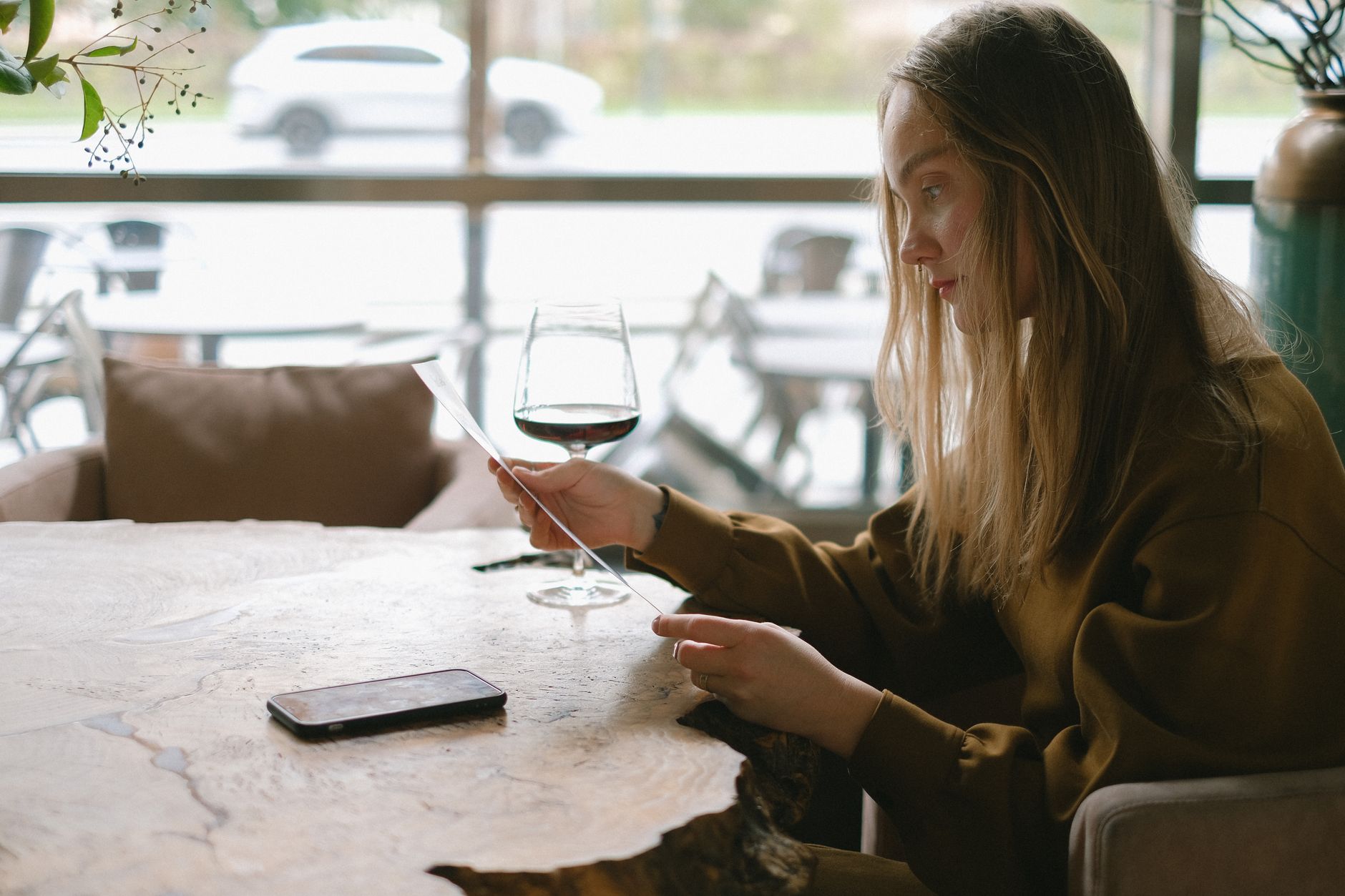 Young woman enjoying a whisky cocktail solo at a contemporary airport bar counter