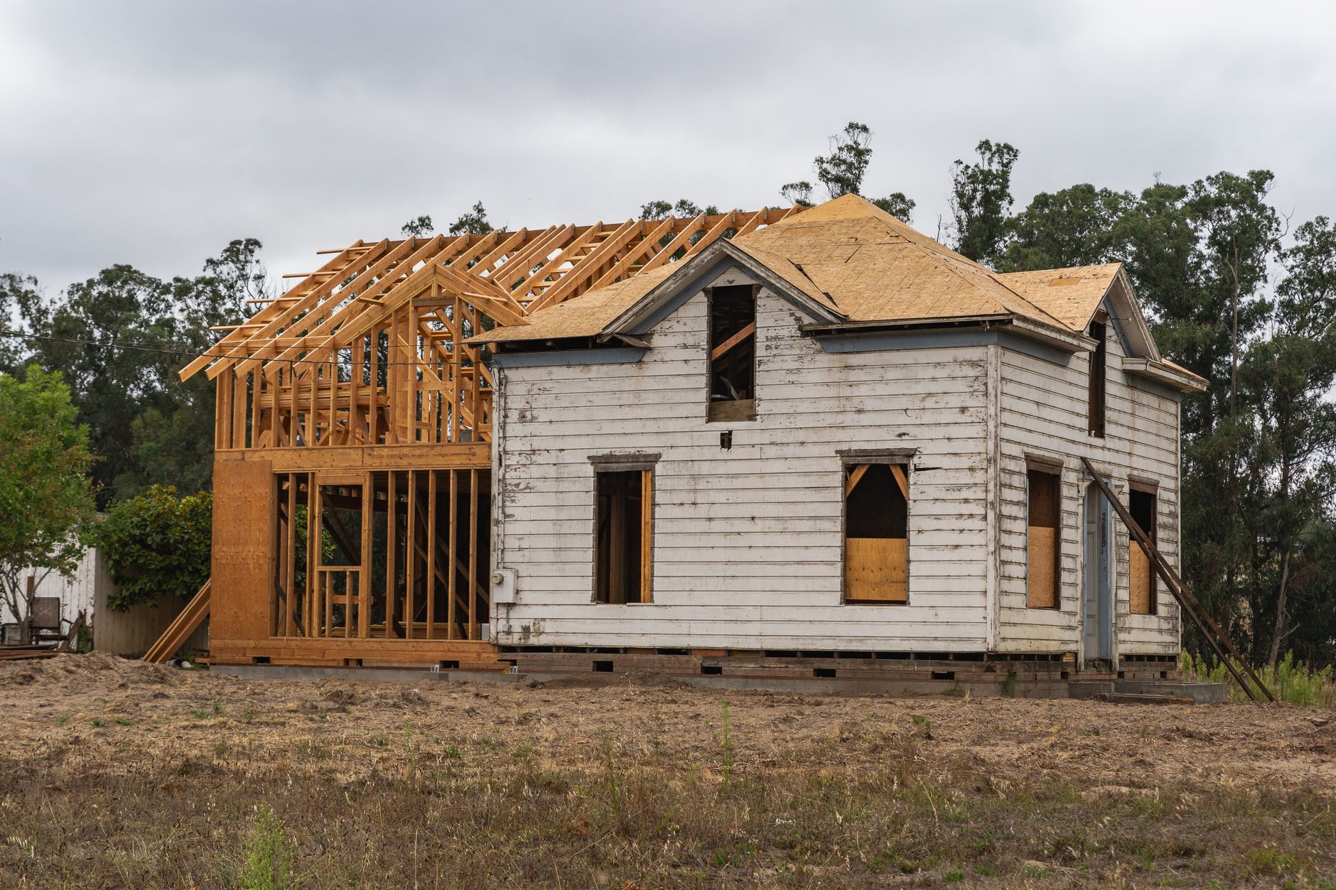 Construction workers framing a residential home addition with wooden beams and structural framework