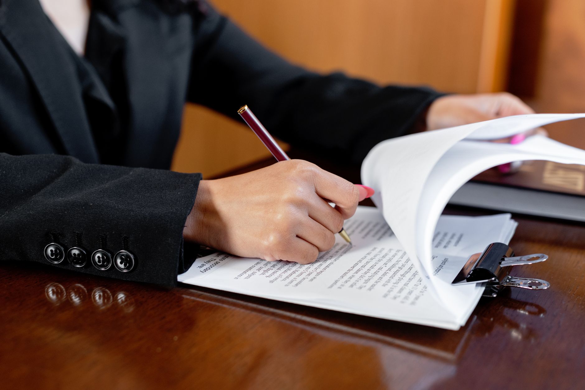Individual reviewing contract documents and legal paperwork at a desk