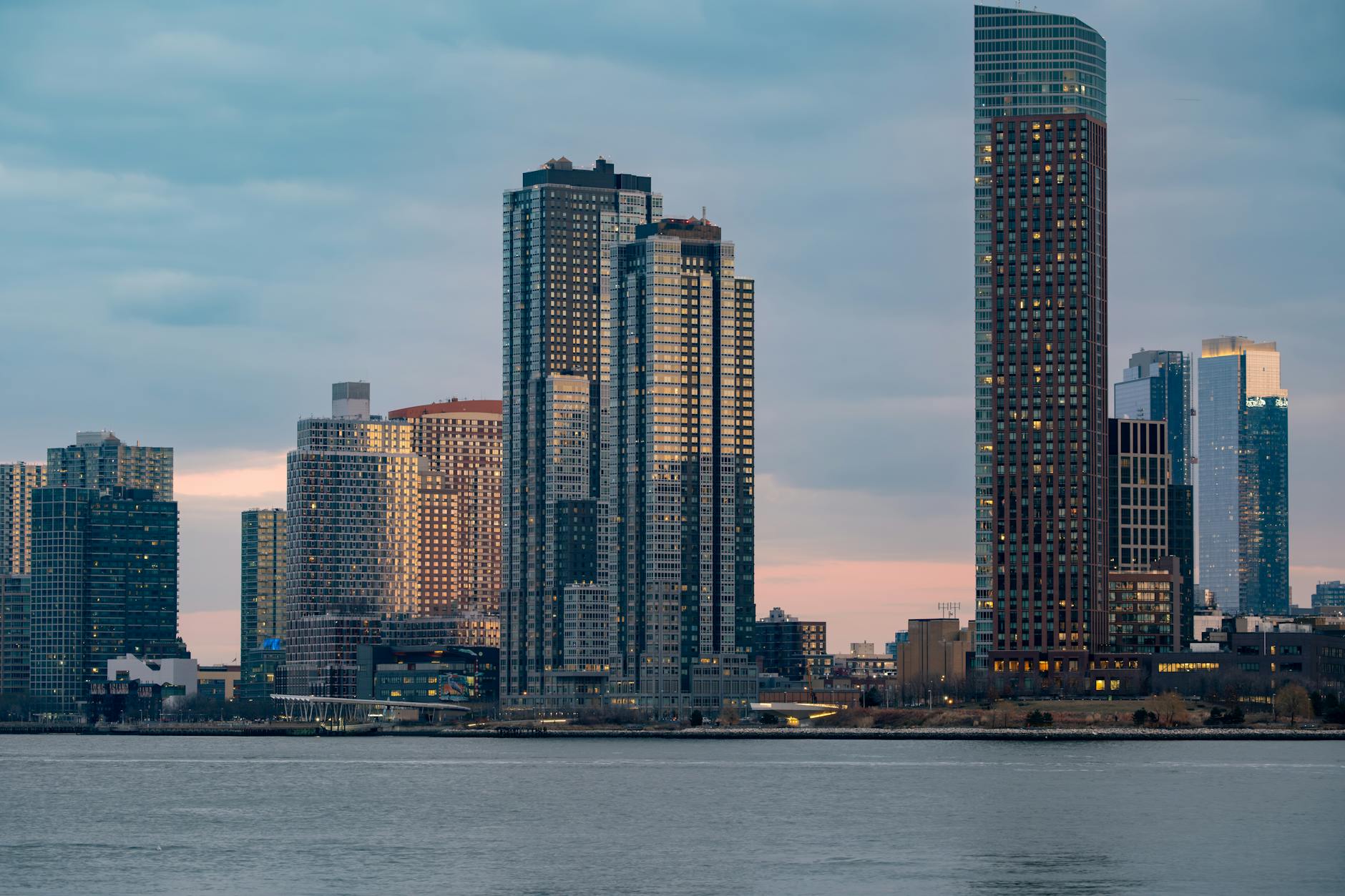 Modern multifamily residential building with glass and brick facade in New York City skyline