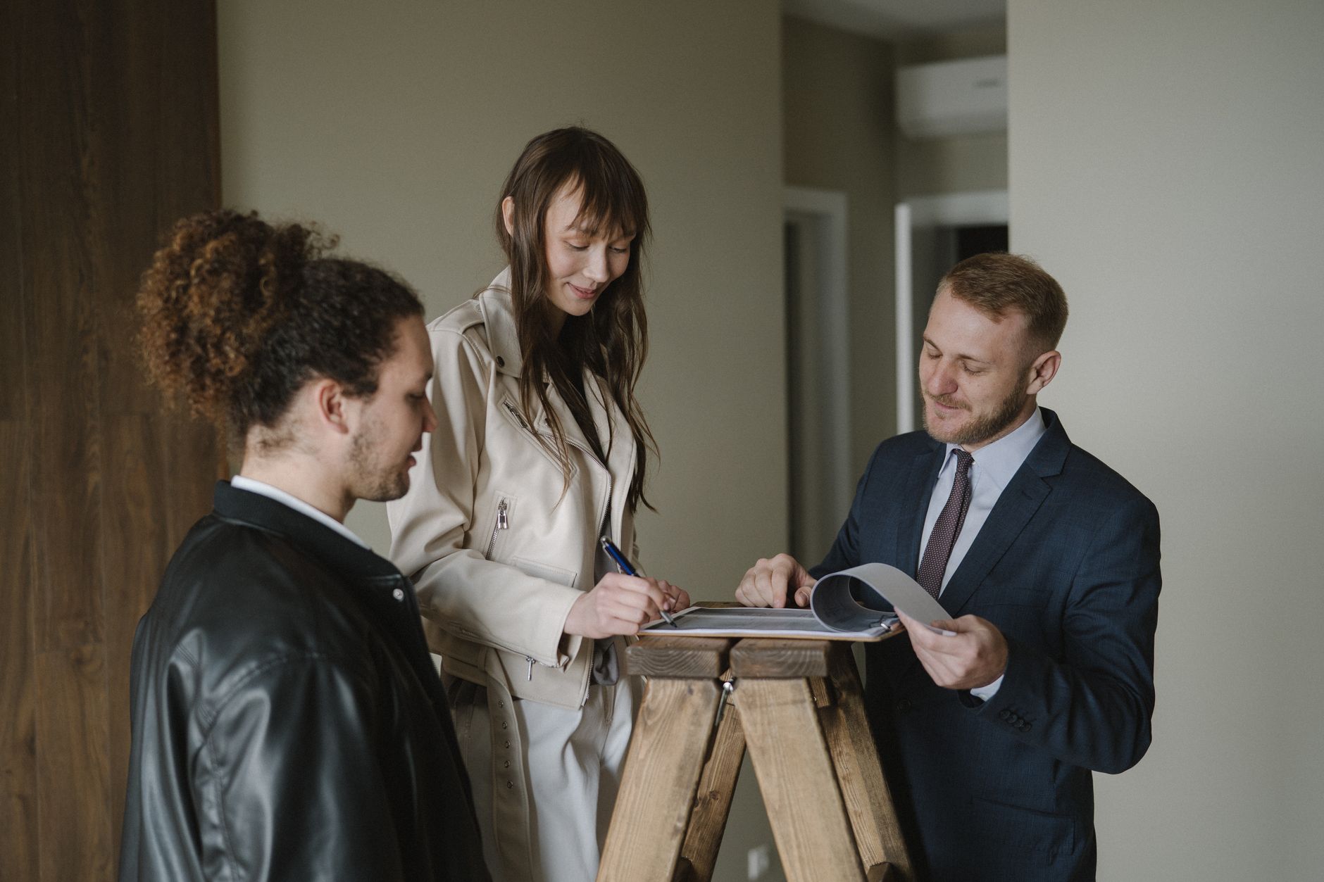 Commercial real estate closing with documents, pen, and handshake between buyer and agent in modern office