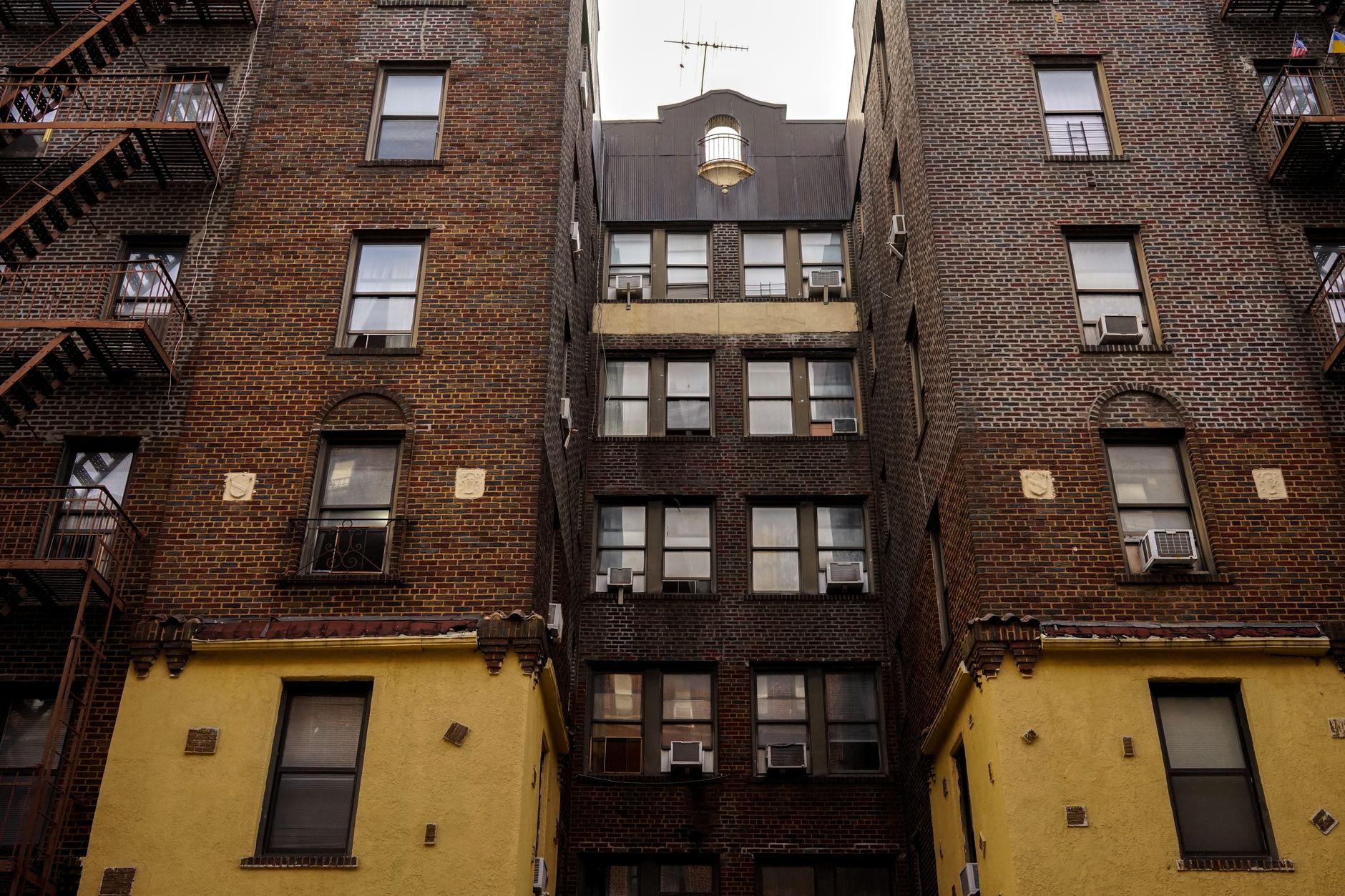 Modern NYC apartment building facade with large windows and fire escapes in residential neighborhood