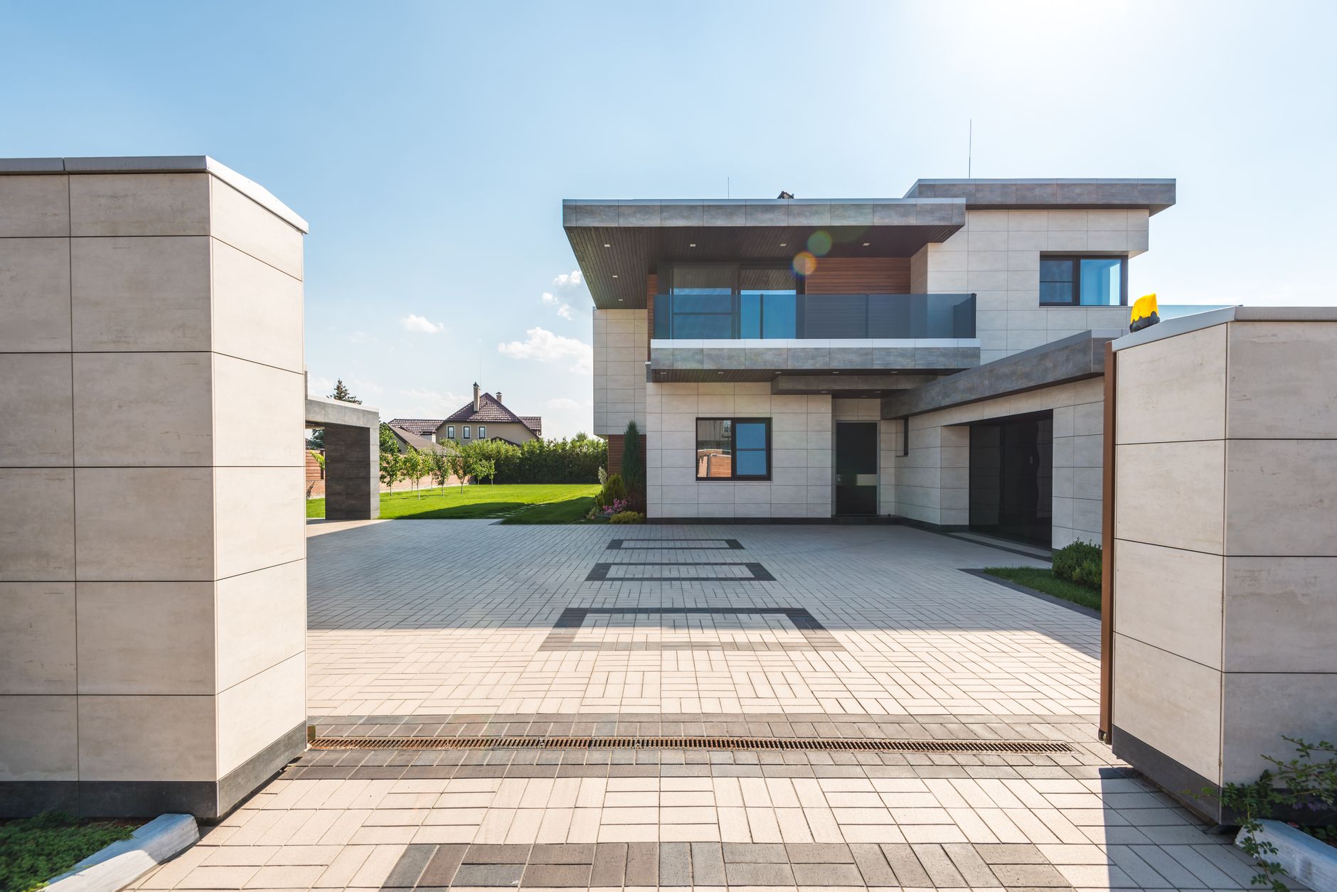 Modern electric driveway gate installed at residential property entrance with stone pillars