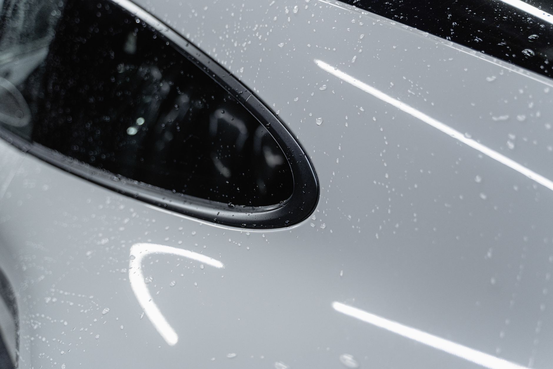 Professional applying protective coating to car paint surface for weather resistance