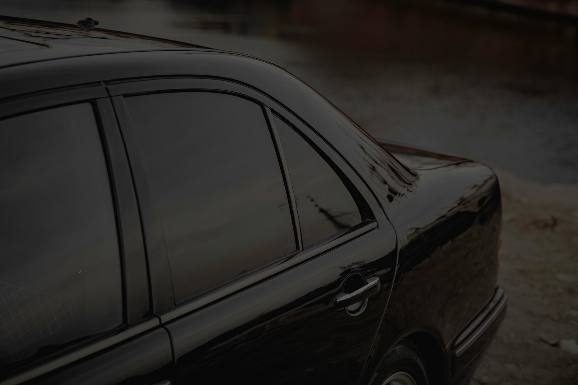 Professional technician applying dark tint film to a car window during installation service