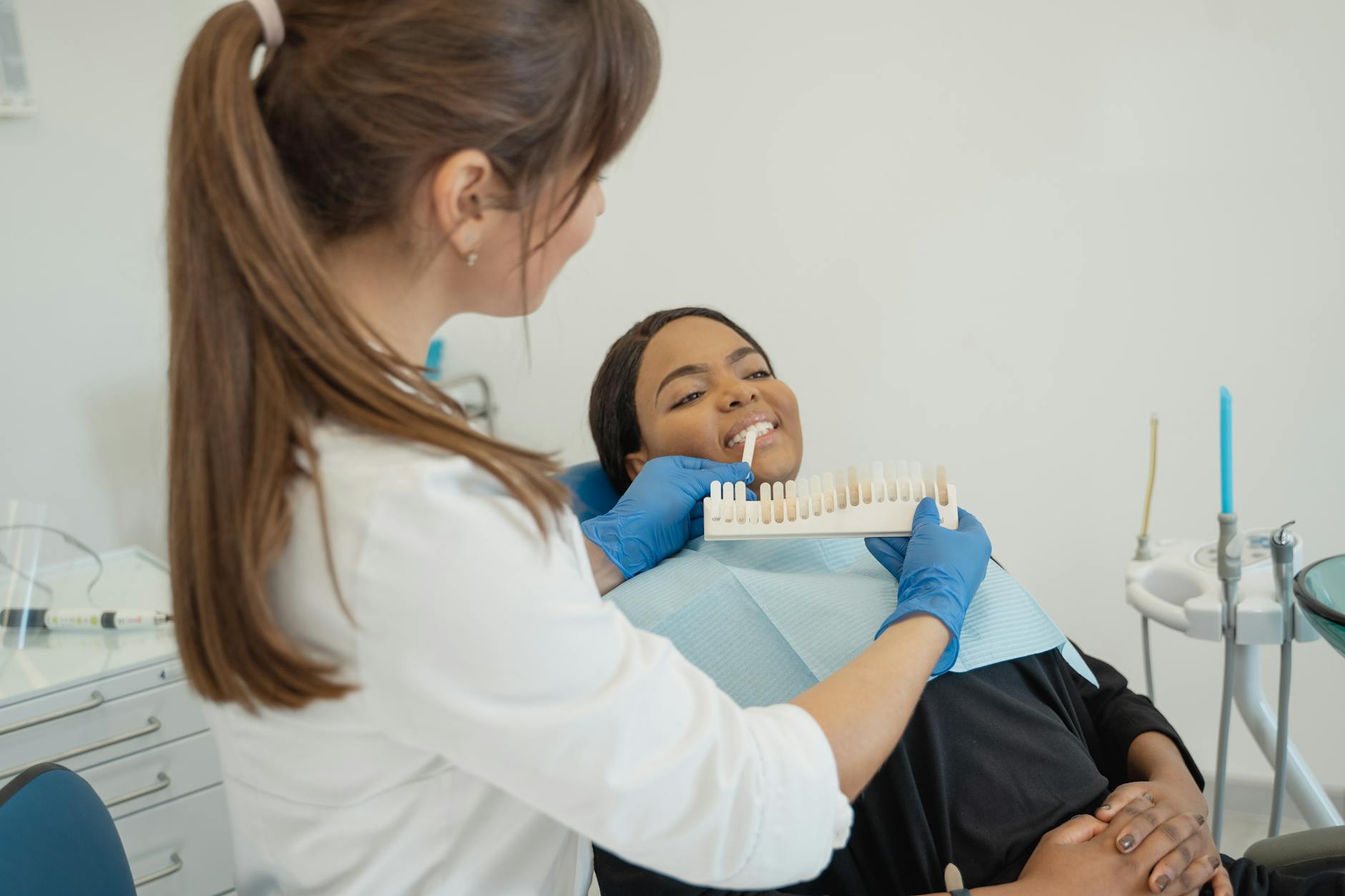 Dentist examining patient in dental chair with modern crown restoration technology and equipment visible