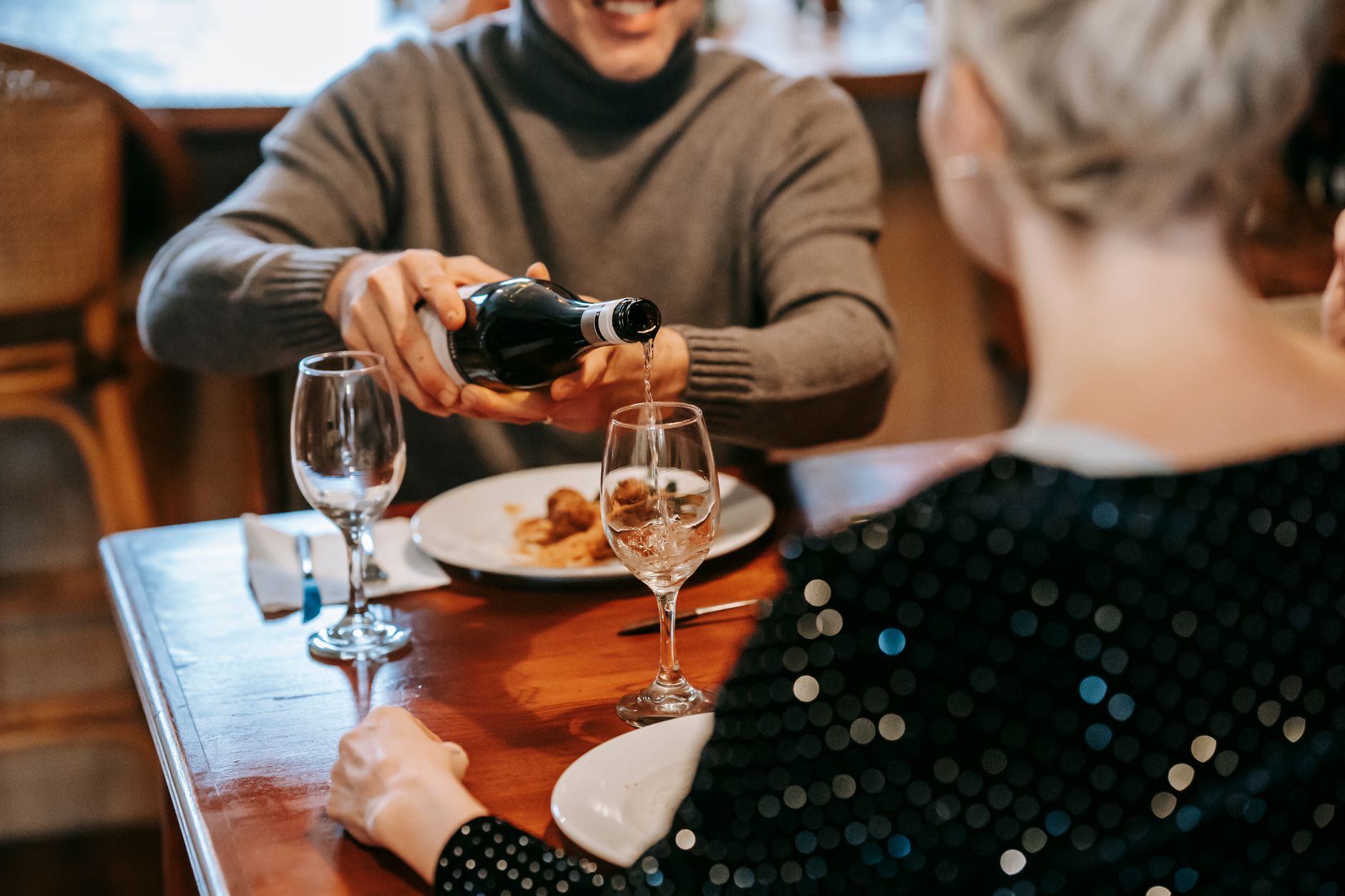 Well-dressed couple enjoying an intimate dinner date at a candlelit restaurant table with wine glasses