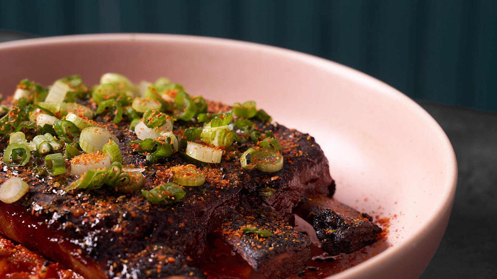 Glazed short rib topped with sliced scallions on a pink plate at 8282