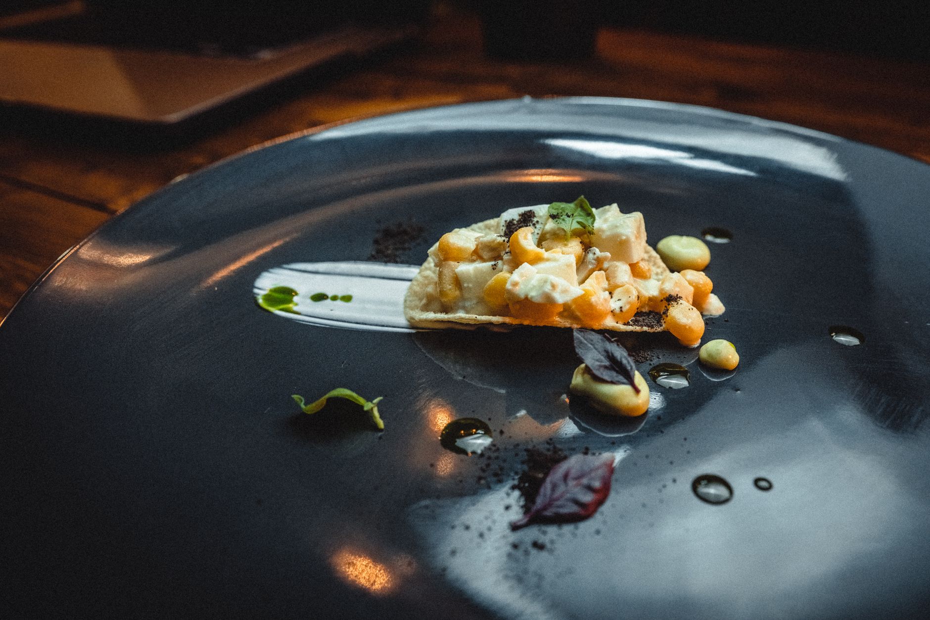 Gourmet appetizer creatively styled on a black plate in a fine dining setting, emphasizing visual artistry.