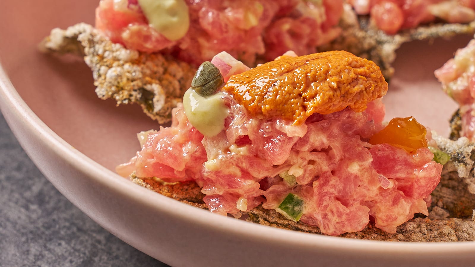 Tuna tartare topped with uni and capers, served with crisp seaweed chips at 8282