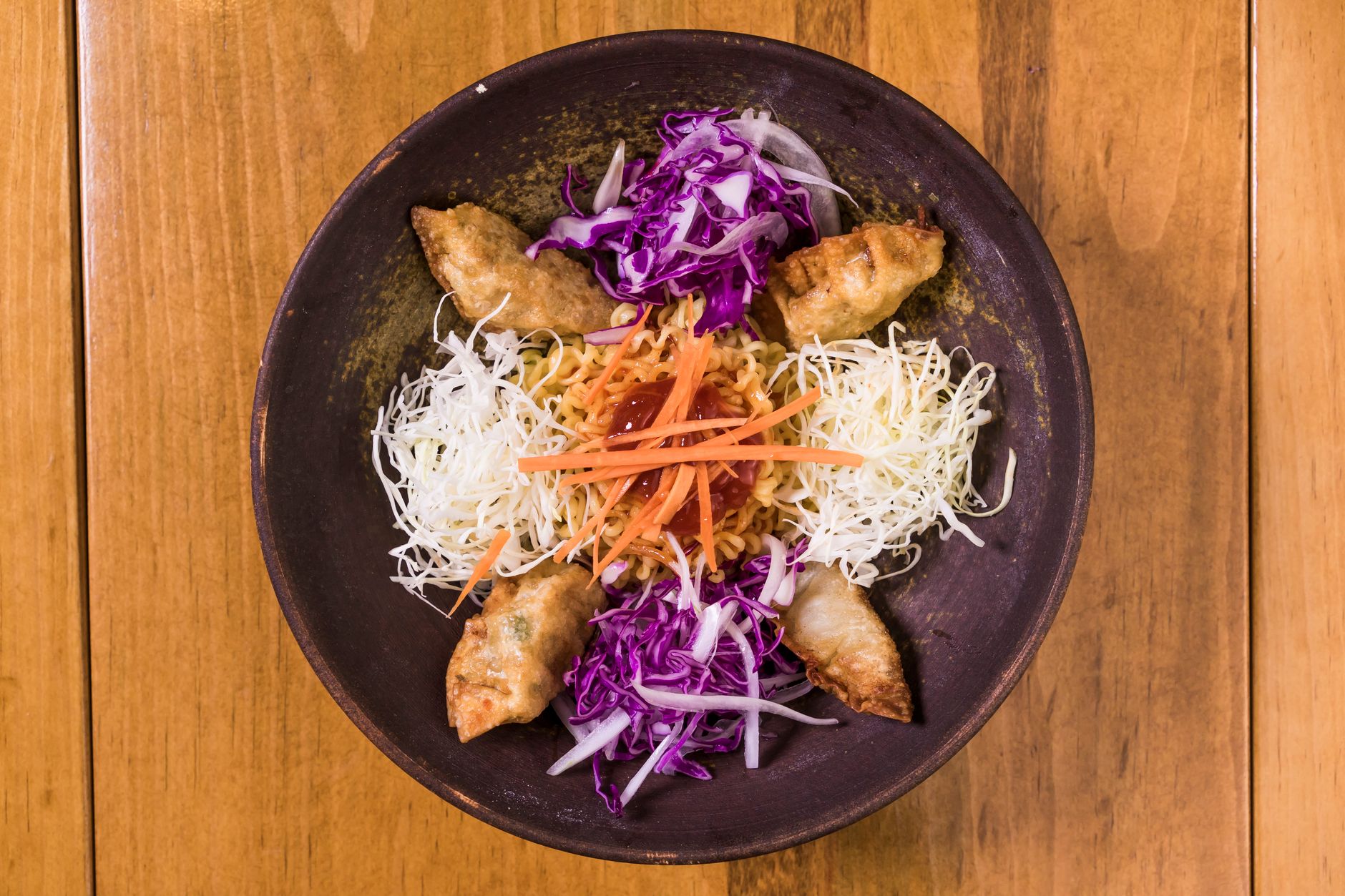Overhead shot of a vibrant Korean dish with dumplings, cabbage, and carrots.