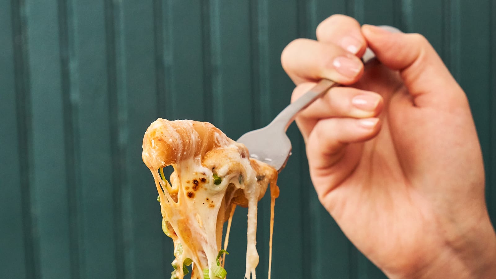 Melted cheese pulled from a bubbling Korean corn cheese skillet at 8282