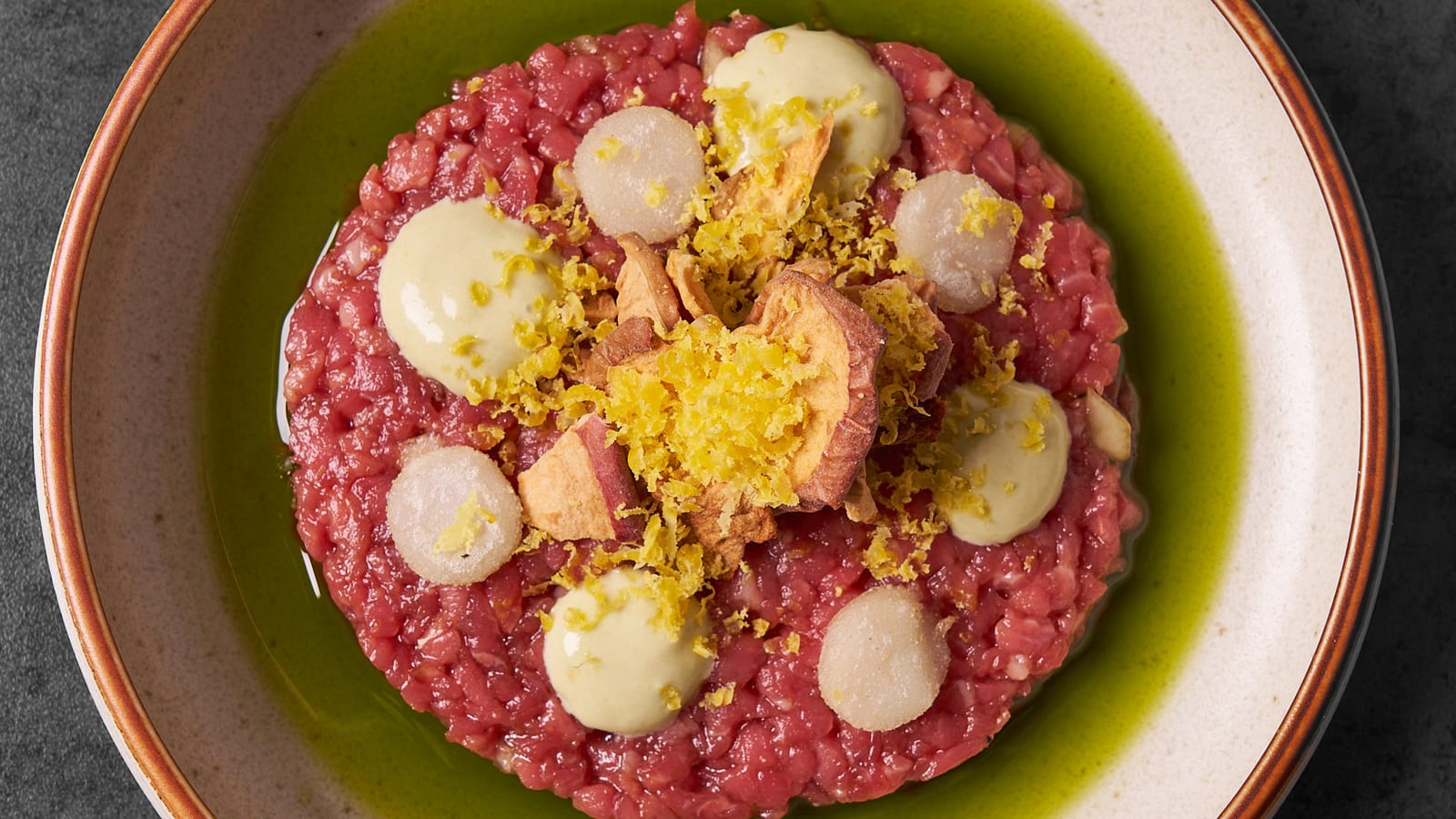 Beef tartare with cured egg yolk and aioli on a green-rimmed plate at 8282