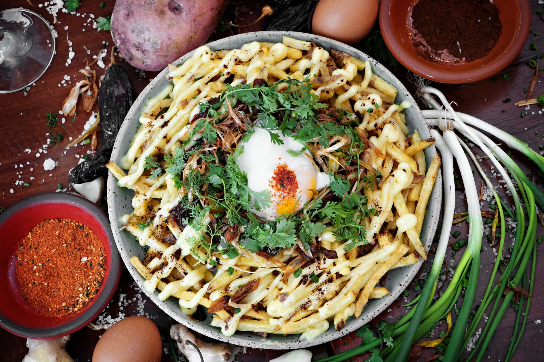 Delicious truffle fries topped with a poached egg, drizzled with sauce, and garnished with fresh herbs.