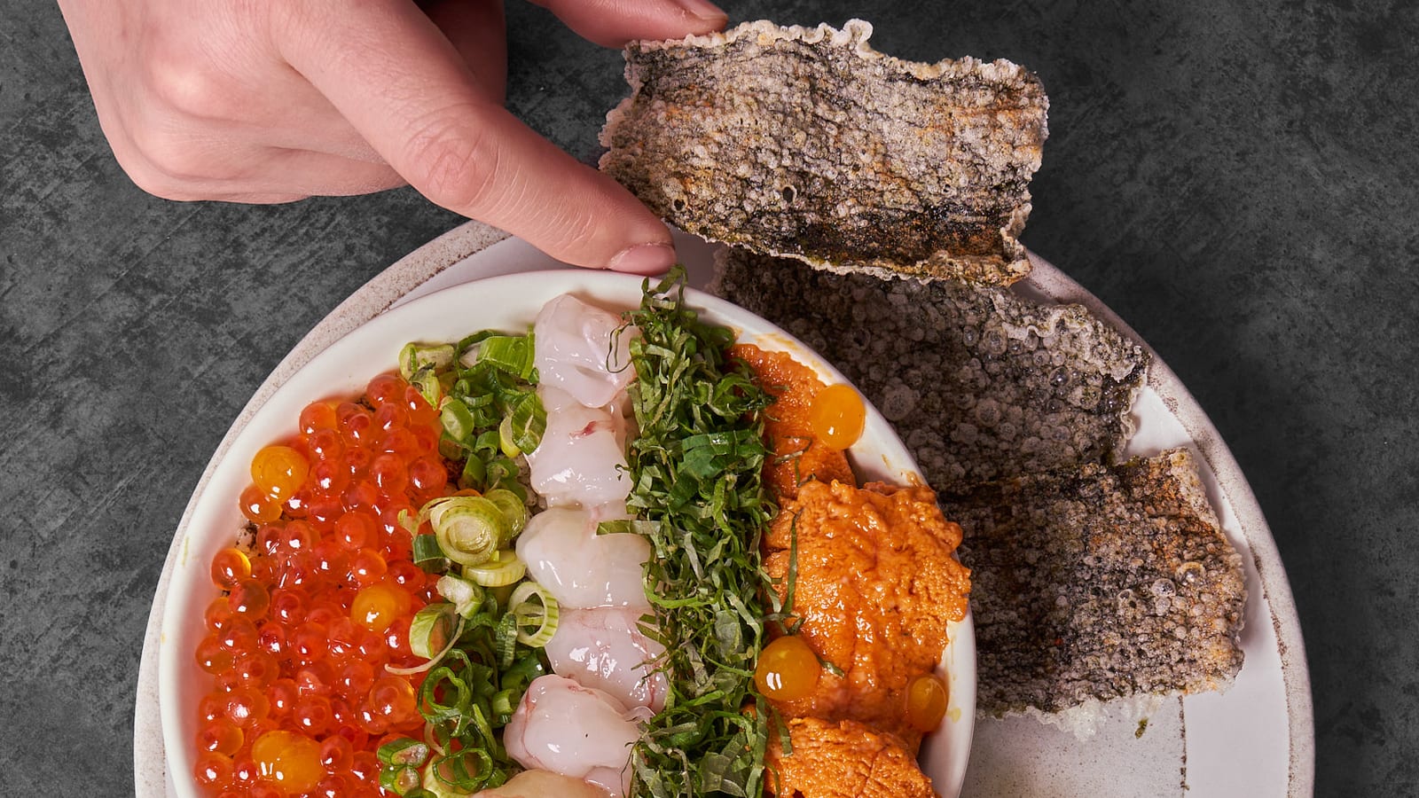 Composed raw fish bowl with uni, salmon roe and shiso, served with seaweed crisps