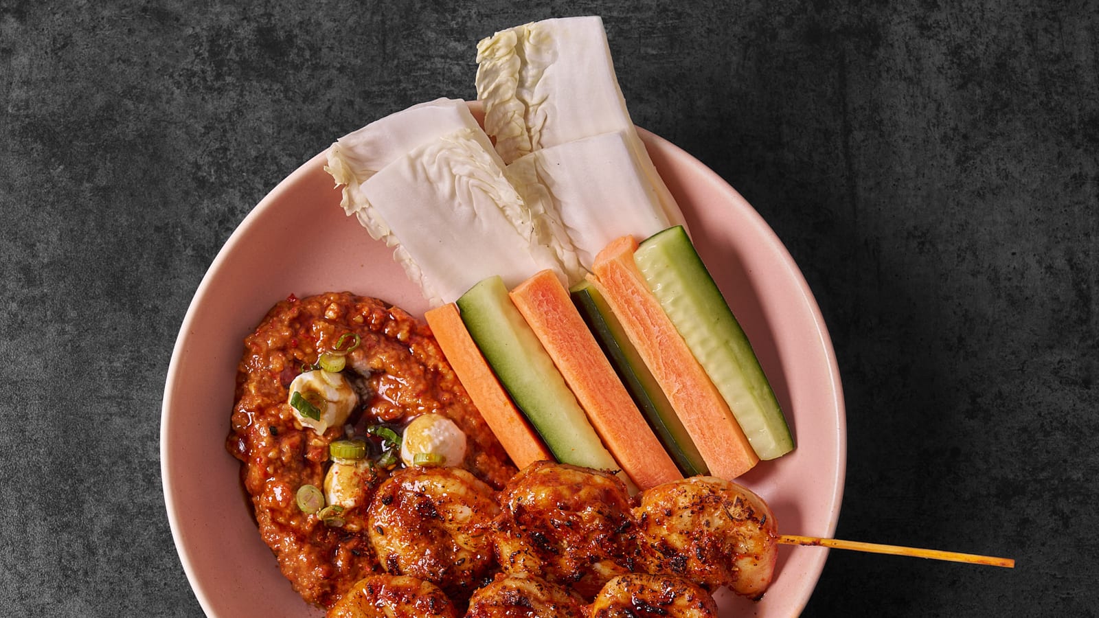 Korean fried chicken skewers with cucumber and carrot batons in a pink bowl at 8282